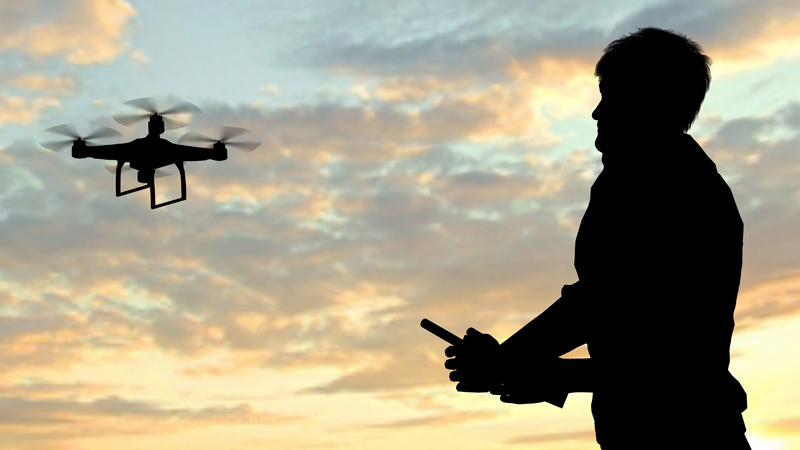 man operating of flying drone quadrocopter at sunset